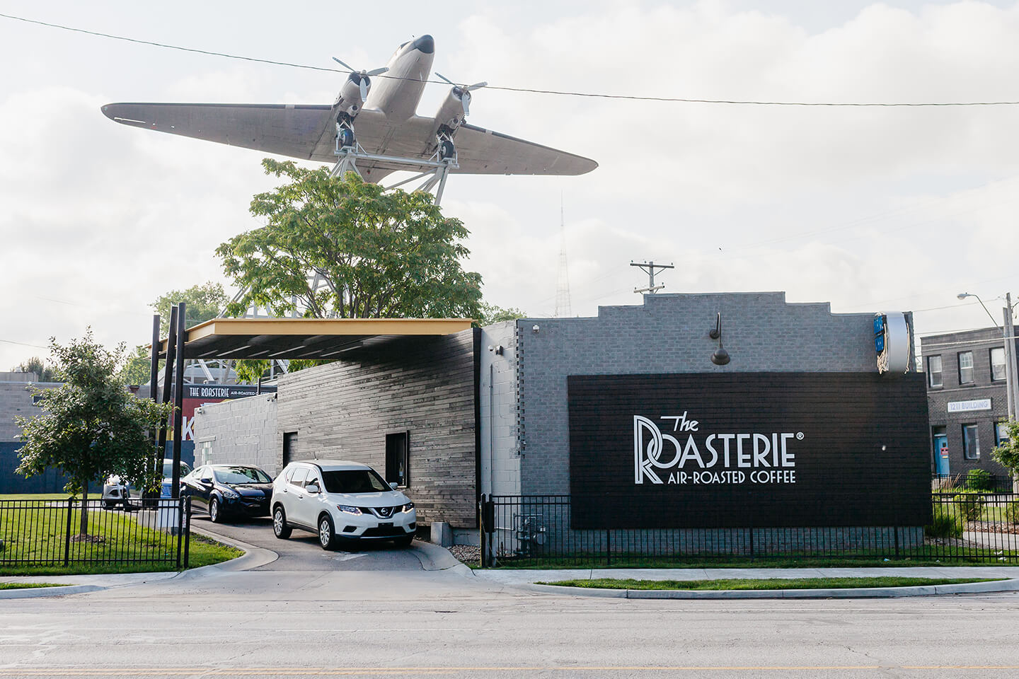 The Roasterie air-roasted coffee drive thru location. There is a massive model airplane hanging above drive thru.