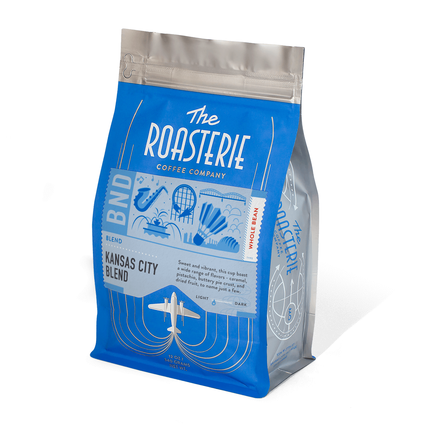 Kansas City Blend coffee bag from The Roasterie featuring vibrant blue packaging with art deco-inspired design elements, aircraft motif, and silver accents, showcasing their signature coffee blend with caramel and pistachio notes