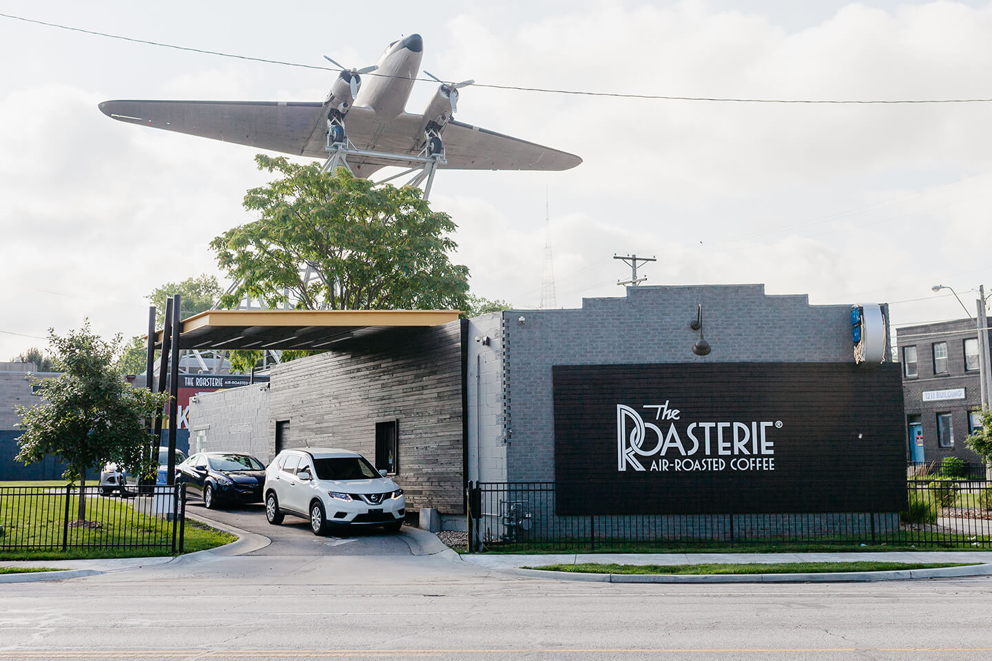 The Roasterie air-roasted coffee drive thru location. There is a massive model airplane hanging above drive thru. 