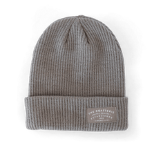 Load image into Gallery viewer, Knit Patch Beanie in heather gray ribbed texture with folded cuff, featuring a leather patch with Kansas City branding. Classic winter beanie style with vertical knit pattern and clean, minimalist design against white background.
