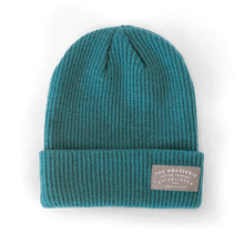 Load image into Gallery viewer, Knit Patch Beanie in vibrant teal color with ribbed texture, featuring a folded cuff and gray branded patch. Warm winter hat with classic beanie styling and vertical knit pattern, perfect for showing Kansas City pride.
