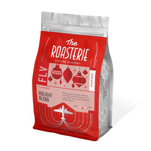 Holiday Blend Decaf coffee bag from The Roasterie featuring red and silver packaging with vintage-style holiday ornament illustrations and art deco design elements. 12oz resealable bag with festive seasonal branding and airplane logo.
