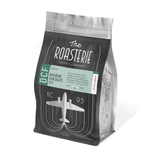 Bavarian Chocolate Decaf coffee bag by The Roasterie featuring an art deco design with airplane motif in black and teal colors, displaying retro-style typography and resealable packaging for premium decaffeinated coffee with chocolate flavoring.
