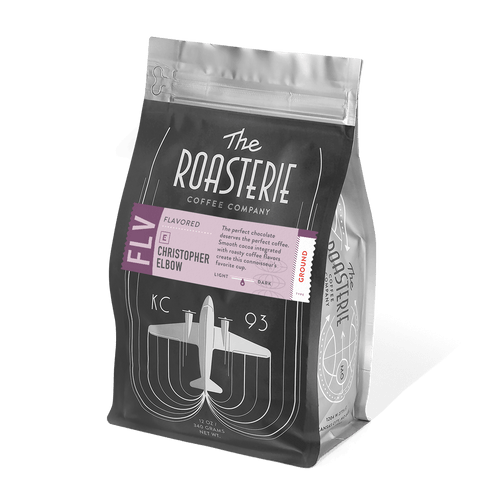 Christopher Elbow Cafe au Chocolat coffee bag from The Roasterie featuring a black package design with purple accents and vintage aircraft illustration, showcasing premium coffee blend with cocoa notes in resealable packaging