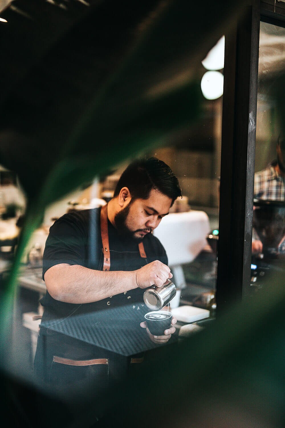 barista pouring milk into coffee